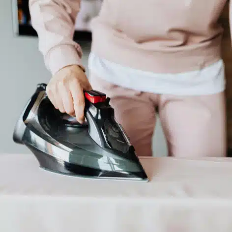 Une personne repasse un drap.