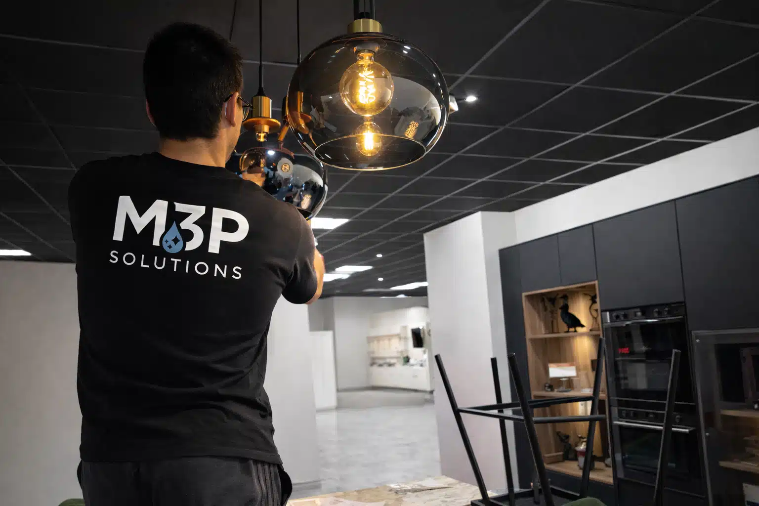 Un homme de M3P Solutions, entreprise de nettoyage à Clermont-Ferrand, réalise le dépoussiérage d'un luminaire.