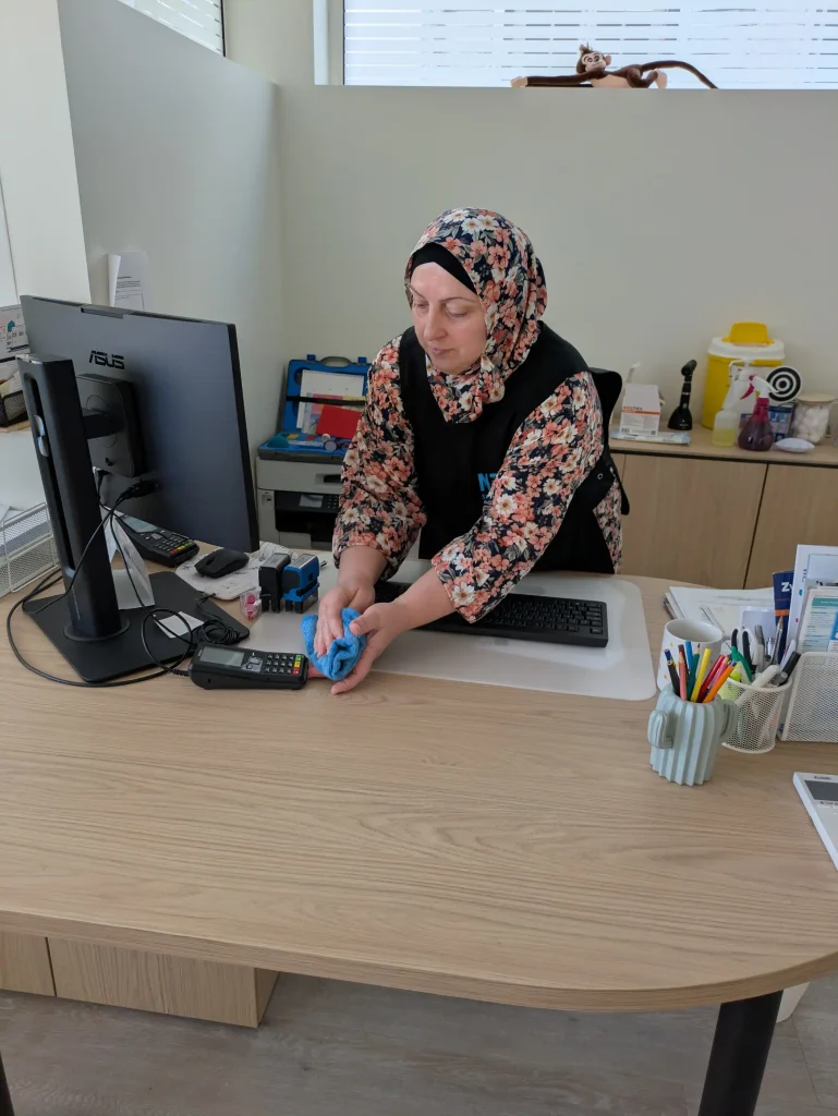Une salariée M3P Solution fait la poussière sur un bureau.