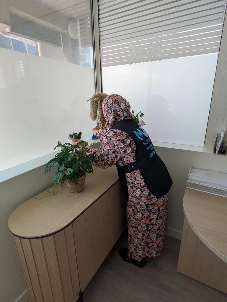 Une salariée M3P Solution fait la poussière dans un bureau.