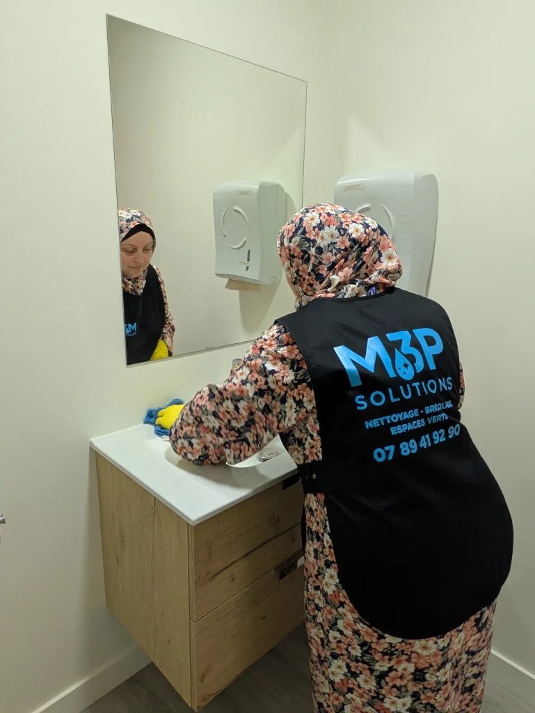 Une salariée M3P Solution nettoie un évier.