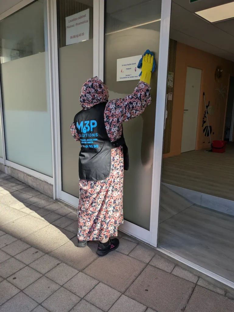 Une salariée M3P Solution nettoie la devanture d'un cabinet médical.
